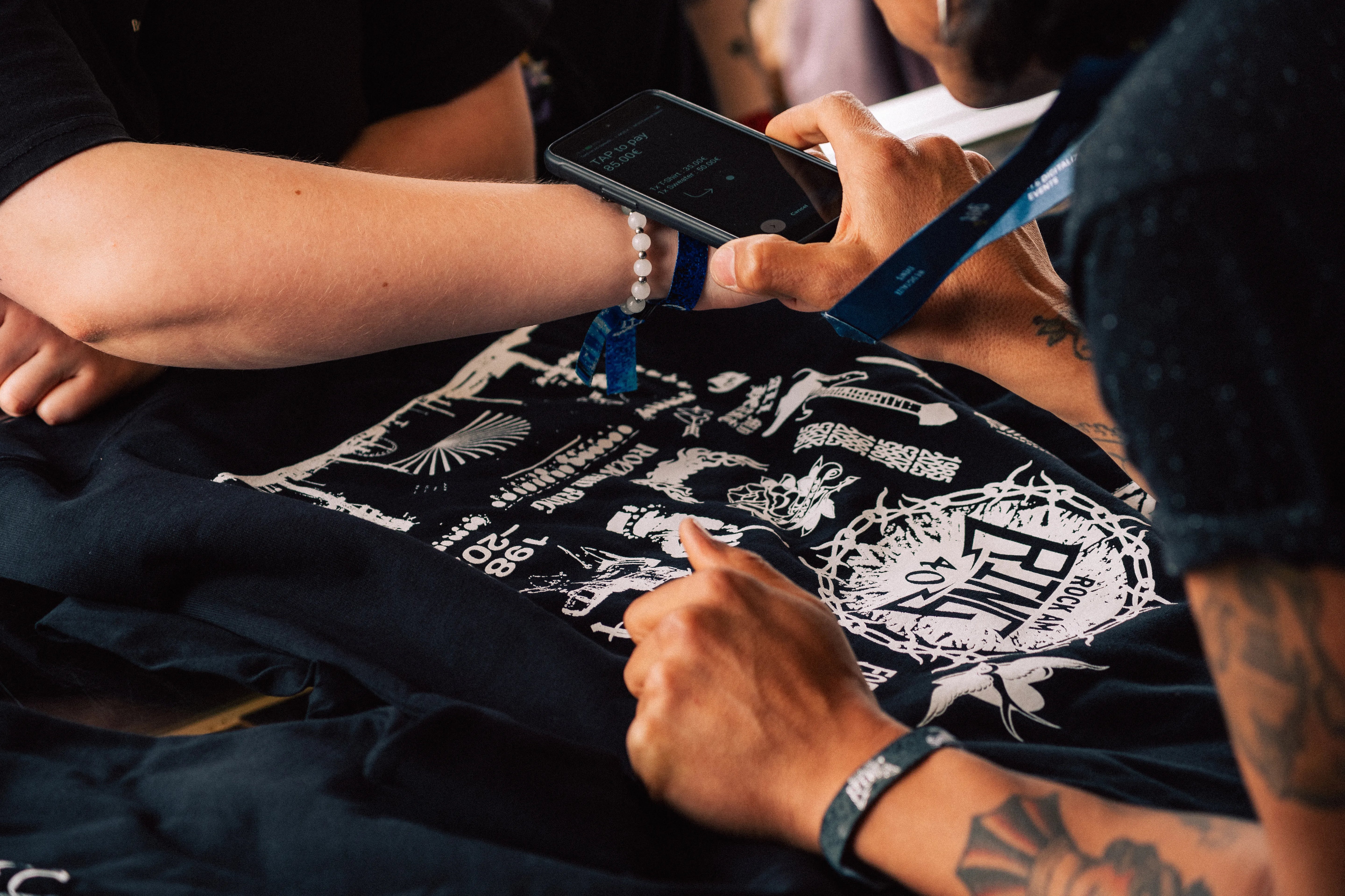Person bezahlt Merchandise mit dem Rock am Ring Festival Bändchen